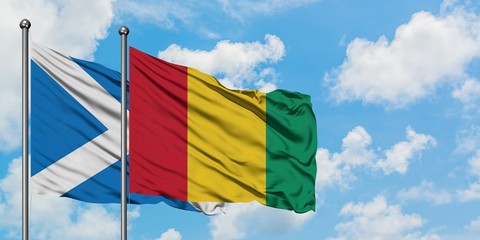 Scotland and Guinea flag waving in the wind against white cloudy blue sky together. Diplomacy concept, international relations.