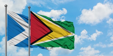 Scotland and Guyana flag waving in the wind against white cloudy blue sky together. Diplomacy concept, international relations.