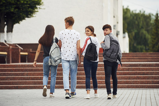 Looking behind. Rear view. Group of young students in casual clothes near university at daytime
