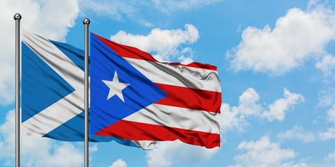 Scotland and Puerto Rico flag waving in the wind against white cloudy blue sky together. Diplomacy concept, international relations.