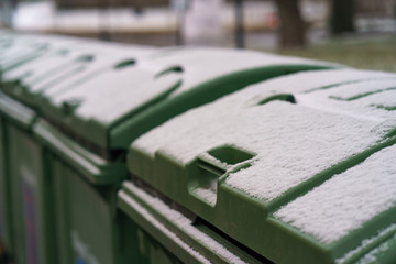 First snow in city Moscow. Calmness and freshness. Green waste bins are covered by first snow. They look clean. Consepts of cleaness and freshness.
