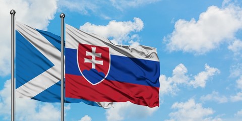 Scotland and Slovakia flag waving in the wind against white cloudy blue sky together. Diplomacy concept, international relations.