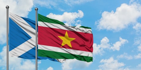 Scotland and Suriname flag waving in the wind against white cloudy blue sky together. Diplomacy concept, international relations.