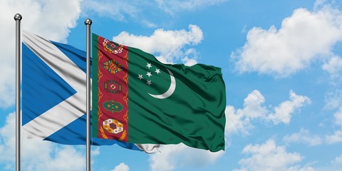 Scotland and Turkmenistan flag waving in the wind against white cloudy blue sky together. Diplomacy...