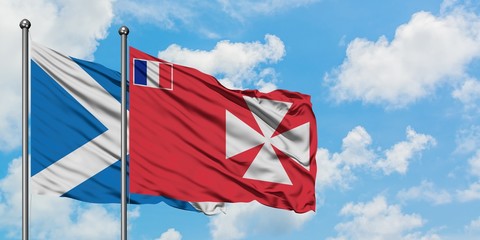 Scotland and Wallis And Futuna flag waving in the wind against white cloudy blue sky together....