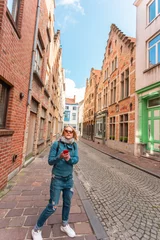 Wall murals Brugges Woman tourist lost in the streets of the city and is looking on his phone how to get further, Bruges, Belgium