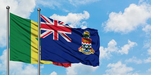 Senegal and Cayman Islands flag waving in the wind against white cloudy blue sky together. Diplomacy concept, international relations.