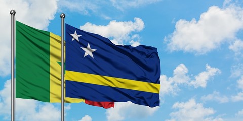 Senegal and Curacao flag waving in the wind against white cloudy blue sky together. Diplomacy concept, international relations.