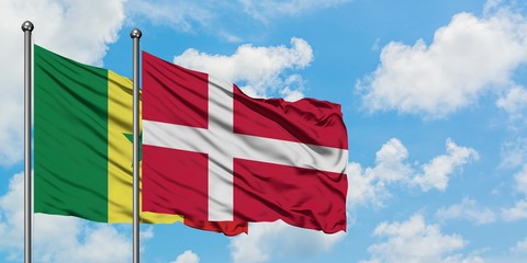 Senegal and Denmark flag waving in the wind against white cloudy blue sky together. Diplomacy...