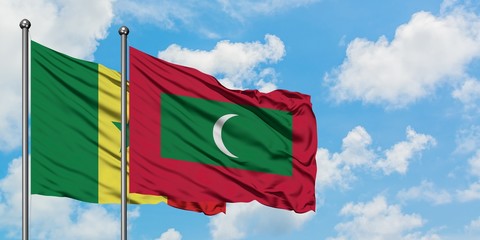 Senegal and Maldives flag waving in the wind against white cloudy blue sky together. Diplomacy...