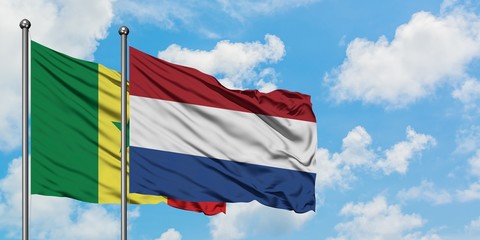 Senegal and Netherlands flag waving in the wind against white cloudy blue sky together. Diplomacy concept, international relations.