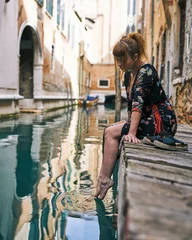 Poster Redhead girl with floral dress sitting near venice canal bare feet © Roberto Vivancos