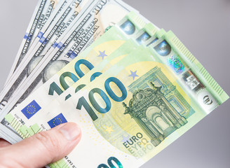 Hand holding hundred dollars and euros bills