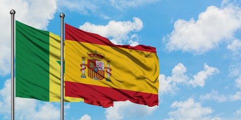 Senegal and Spain flag waving in the wind against white cloudy blue sky together. Diplomacy concept, international relations.