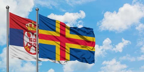 Serbia and Aland Islands flag waving in the wind against white cloudy blue sky together. Diplomacy...