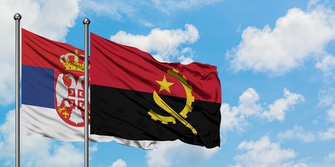 Serbia and Angola flag waving in the wind against white cloudy blue sky together. Diplomacy...