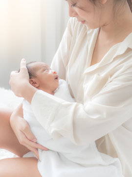 A beautiful Asian woman puts her newborn baby on her body happily and with love