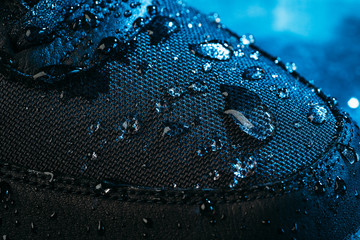 Water drops on waterproof membrane fabric of shoes surface, macro shot. New waterproofing technology for wear and footwear for active lifestyle.
