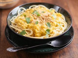 Bowl with spaghetti with a green tomato sauce and vegan walnut parmesan