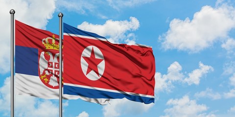 Serbia and North Korea flag waving in the wind against white cloudy blue sky together. Diplomacy concept, international relations.