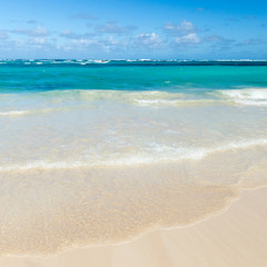 Sea wave on the sand of a tropical beach in a wild turquoise bay