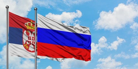 Serbia and Russia flag waving in the wind against white cloudy blue sky together. Diplomacy concept, international relations.