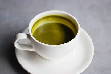 Matcha latte in a white cup on a gray background. Superfood concept.
