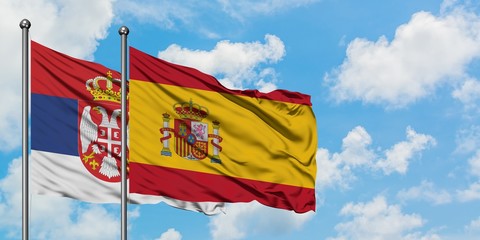 Serbia and Spain flag waving in the wind against white cloudy blue sky together. Diplomacy concept, international relations.