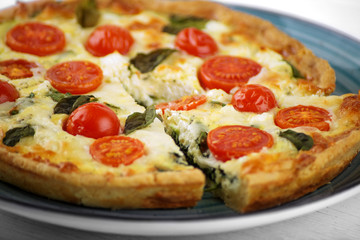 Quiche pie with spinach, cherry and mozzarella. Close-up. The concept of delicious food, recipes.