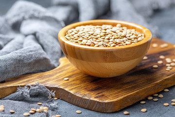 Dry brown lentils in a wooden bowl.