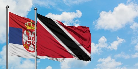 Serbia and Trinidad And Tobago flag waving in the wind against white cloudy blue sky together. Diplomacy concept, international relations.