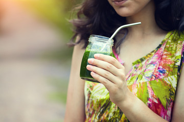 young woman's hand holding healthy green drink, tasty fresh smoothie, copy space, hot summer morning