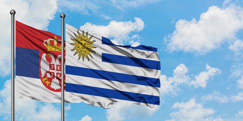 Serbia and Uruguay flag waving in the wind against white cloudy blue sky together. Diplomacy concept, international relations.