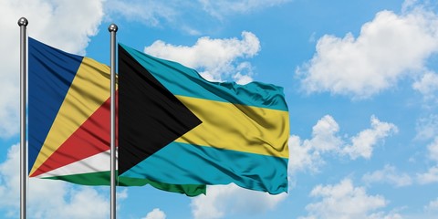 Seychelles and Bahamas flag waving in the wind against white cloudy blue sky together. Diplomacy concept, international relations.