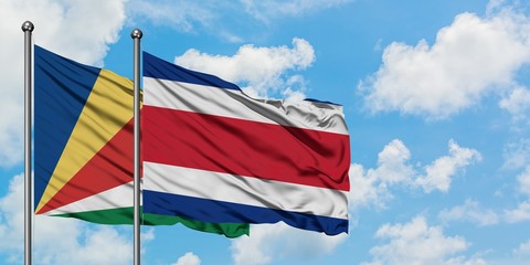 Seychelles and Costa Rica flag waving in the wind against white cloudy blue sky together. Diplomacy concept, international relations.