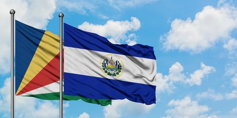 Seychelles and El Salvador flag waving in the wind against white cloudy blue sky together. Diplomacy concept, international relations.