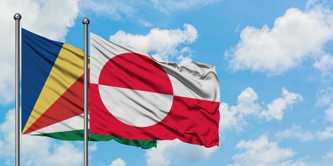Seychelles and Greenland flag waving in the wind against white cloudy blue sky together. Diplomacy concept, international relations.
