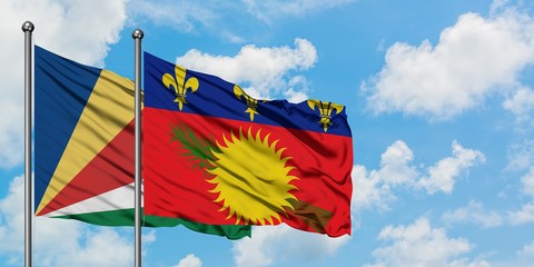 Seychelles and Guadeloupe flag waving in the wind against white cloudy blue sky together. Diplomacy concept, international relations.