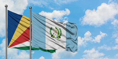 Seychelles and Guatemala flag waving in the wind against white cloudy blue sky together. Diplomacy...