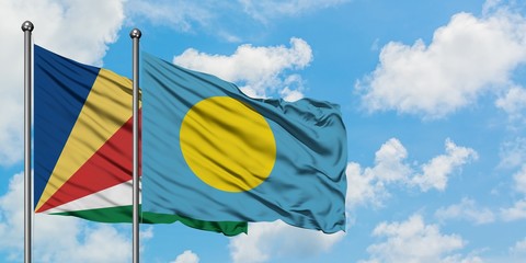 Seychelles and Palau flag waving in the wind against white cloudy blue sky together. Diplomacy...