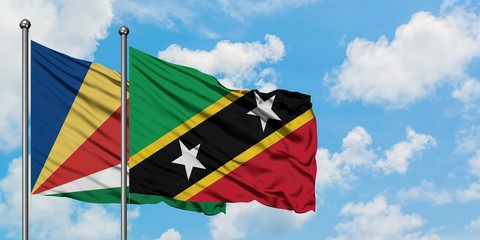 Seychelles and Saint Kitts And Nevis flag waving in the wind against white cloudy blue sky together. Diplomacy concept, international relations.