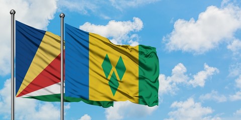 Seychelles and Saint Vincent And The Grenadines flag waving in the wind against white cloudy blue...