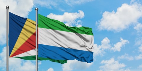Seychelles and Sierra Leone flag waving in the wind against white cloudy blue sky together....