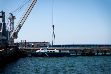 Fototapeta premium in a seaport I raise a yacht with a large crane against a blue sky