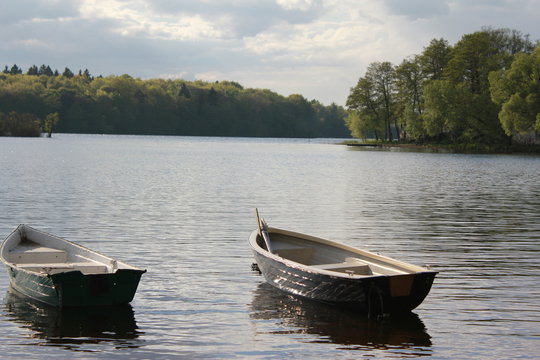 Two boats moored at the shore. A view of a calm lake.