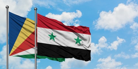 Seychelles and Syria flag waving in the wind against white cloudy blue sky together. Diplomacy...