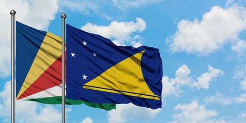 Seychelles and Tokelau flag waving in the wind against white cloudy blue sky together. Diplomacy concept, international relations.