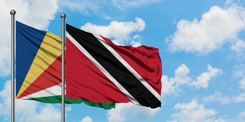 Seychelles and Trinidad And Tobago flag waving in the wind against white cloudy blue sky together....