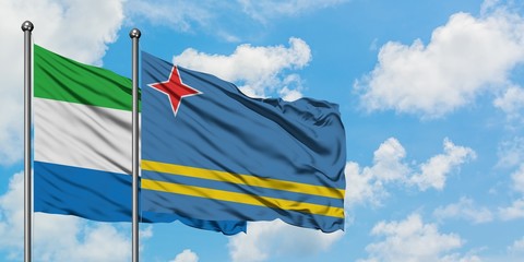 Sierra Leone and Aruba flag waving in the wind against white cloudy blue sky together. Diplomacy...