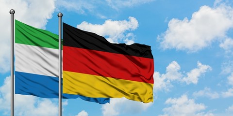 Sierra Leone and Germany flag waving in the wind against white cloudy blue sky together. Diplomacy concept, international relations.